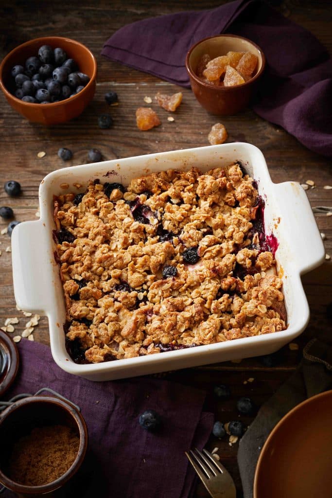 A pan full of apple blueberry crisp on a wooden table