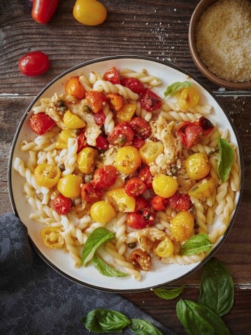 roasted tomato pasta on a white plate and on a wooden table