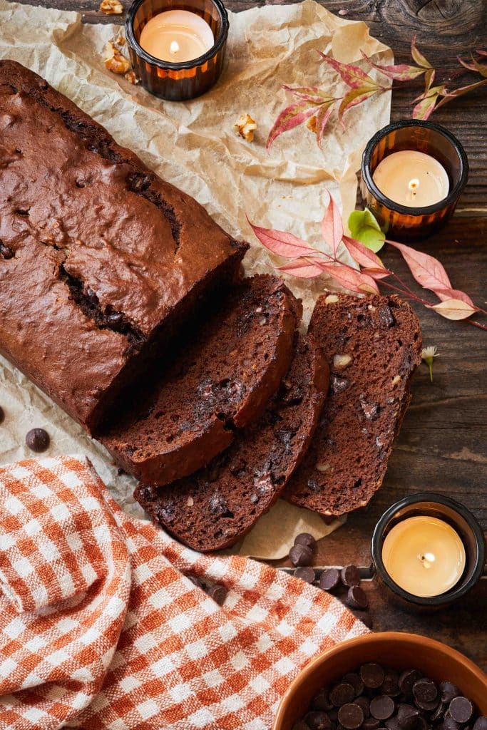 a loaf of chocolate chip banana bread sliced on a piece of brown parchment paper