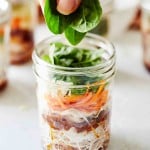 mason jar instant noodles and a hand adding spinach
