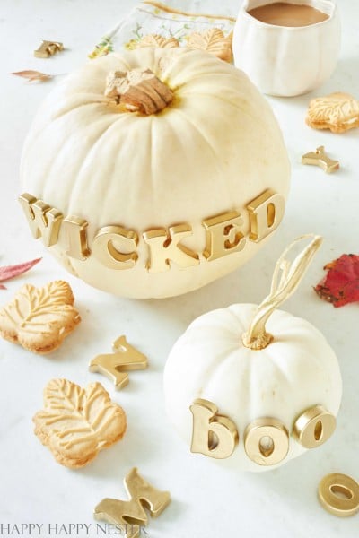 Two white pumpkins that have the words boo and wicked on them