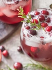 a close up of this cranberry holiday drink in a round glass