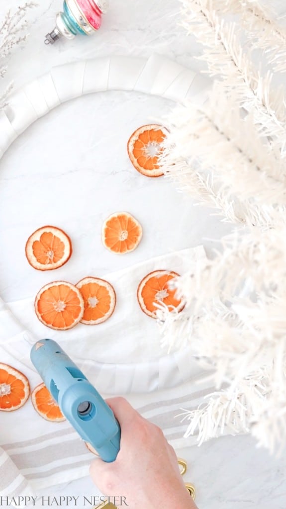 attaching orange dried orange slices with a glue gun