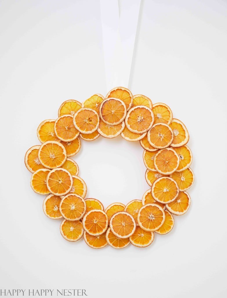 Christmas wreath with orange slices hanging on a white wall