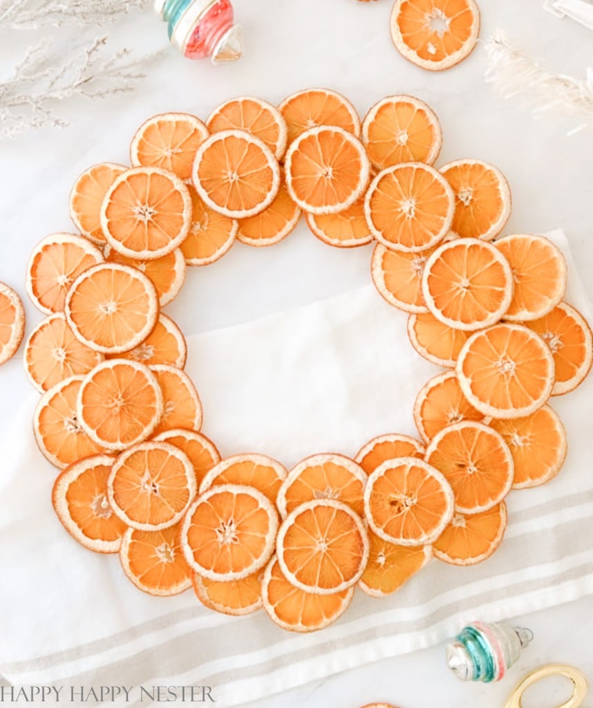 A Christmas wreath with orange slices laying on a white table