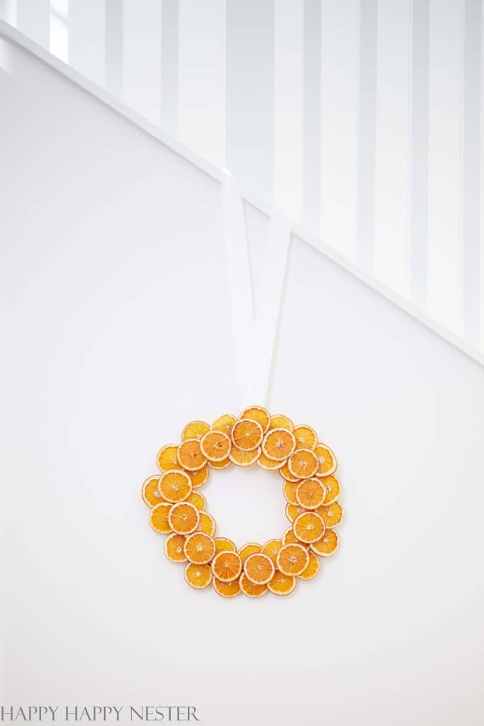A Christmas wreath with orange slices handing on a wall of a stairway