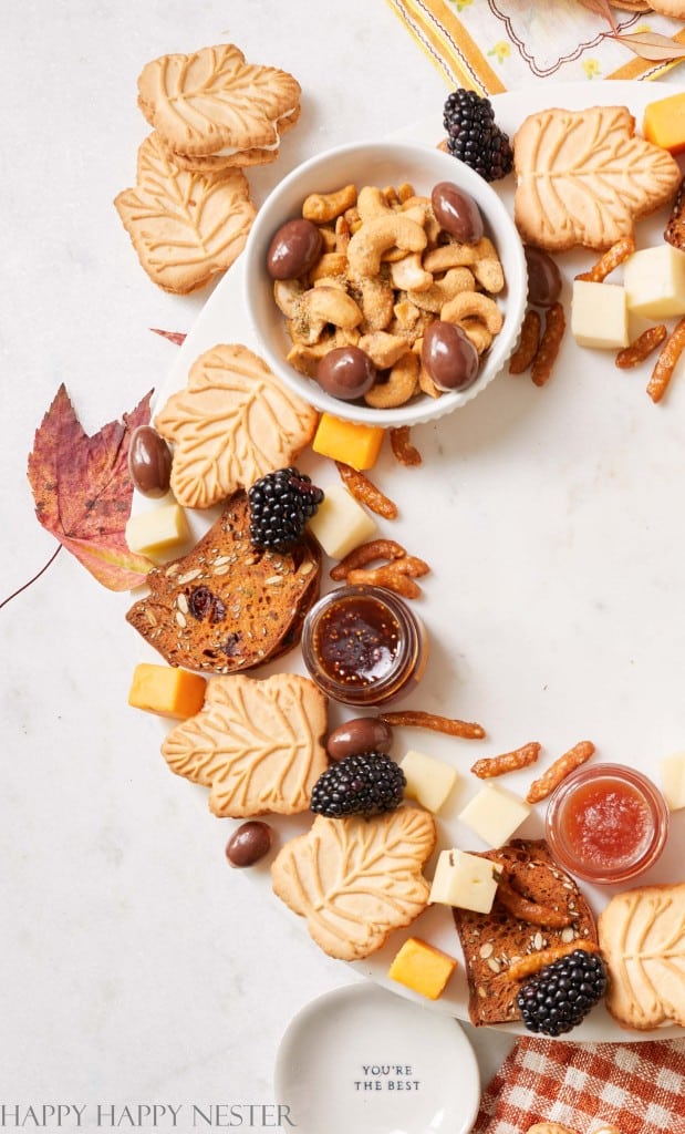 close up of a cheeses, crackers, berries, mini-jams, cookies on a circular marble lazy susan