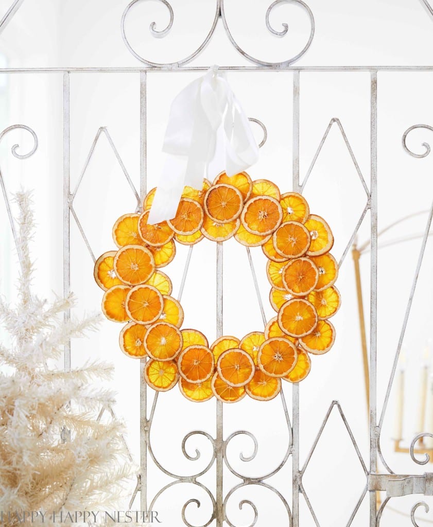 A Christmas Wreath with Orange Slices hanging on a a white wrought iron gate