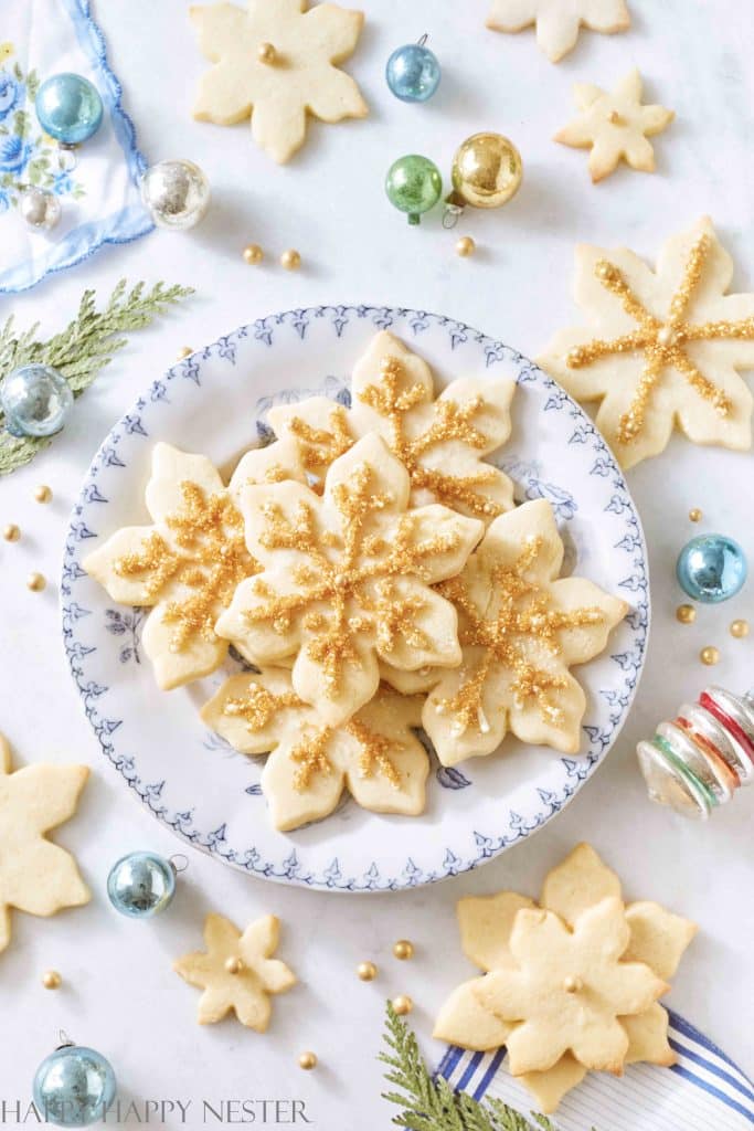 a vintage blue plate full of snowflake sugar cookies decorated with gold sprinkles