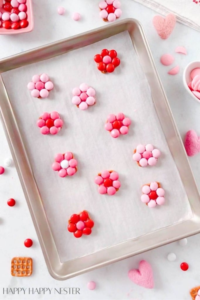 a bunch of pink and red flower pretzels on a baking tray