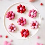 here are the results of the Flower Pretzels Recipe. A bunch of red and pink m&m's flowers on a white cakestand