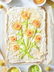 the final product of a big cookie that is frosted and has a scene of a orange flowers on it.