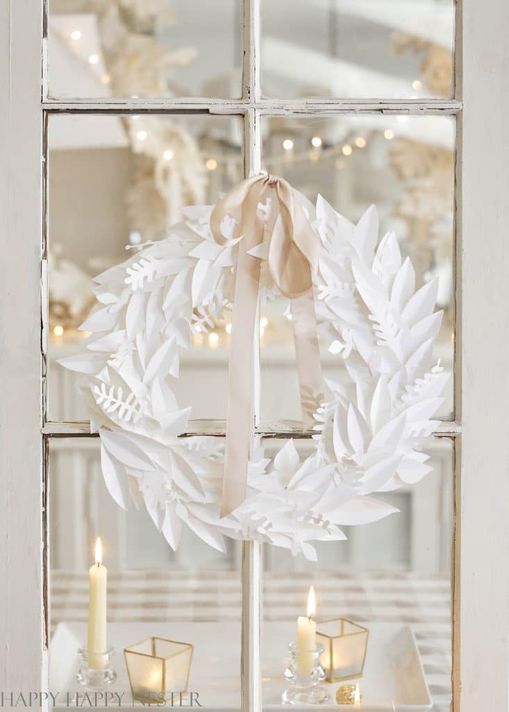 a white paper leaf january winter wreath hanging from a white window pane