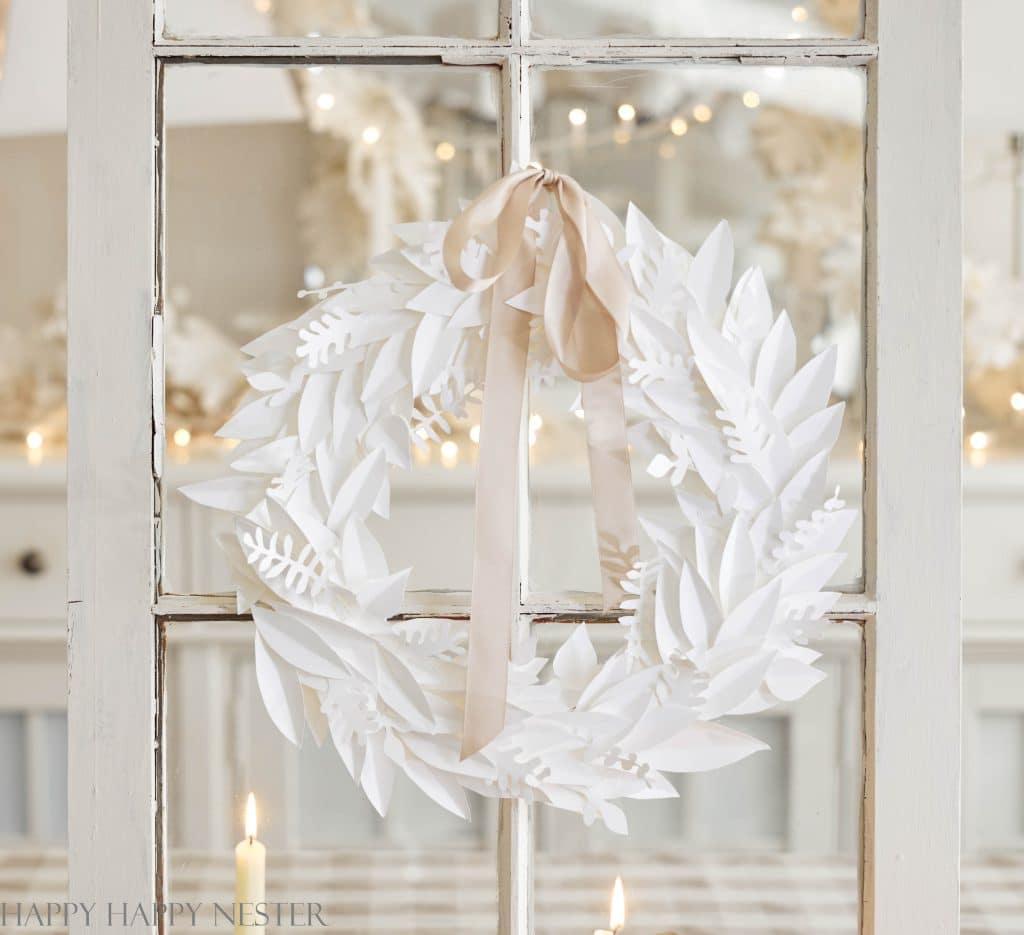 a paper leaf wreath hanging on a white window pane
