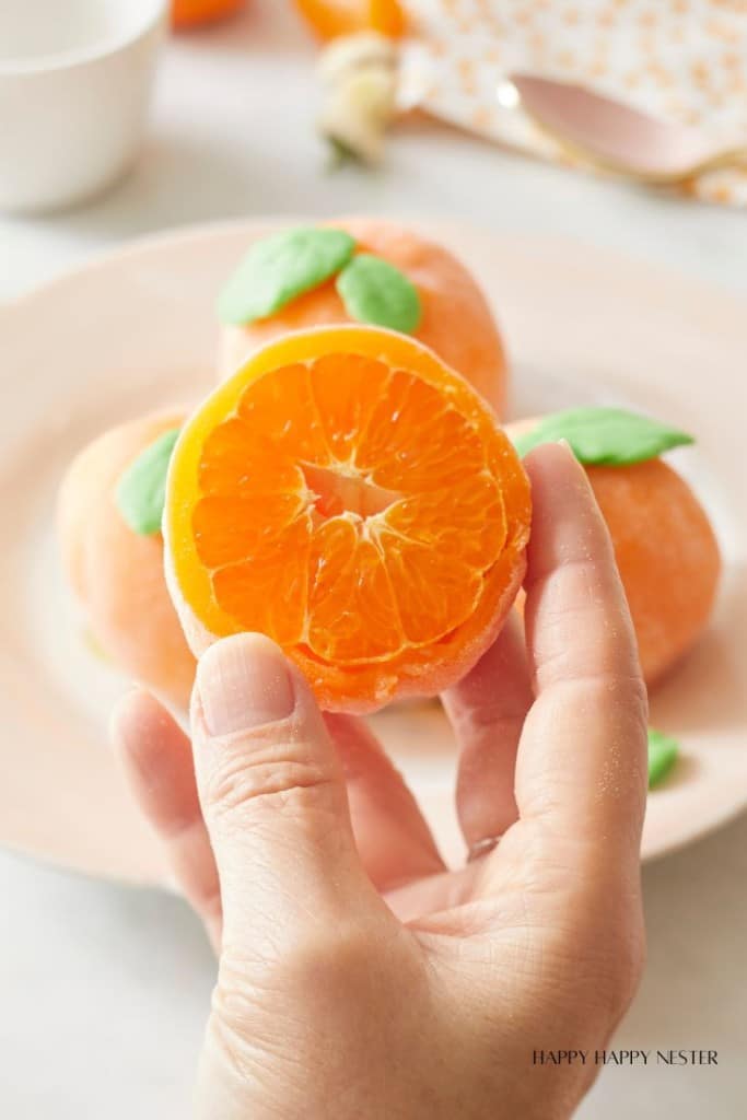 a hand holding a slice of orange mochi