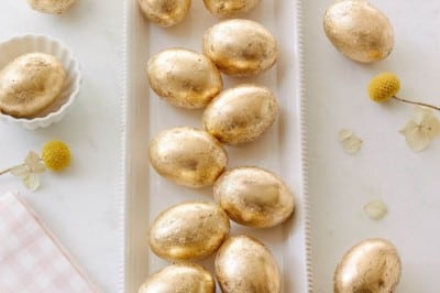 a line of gold leaf faux eggs on a narrow white platter