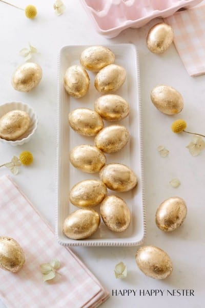 a line of gold leaf faux eggs on a narrow white platter