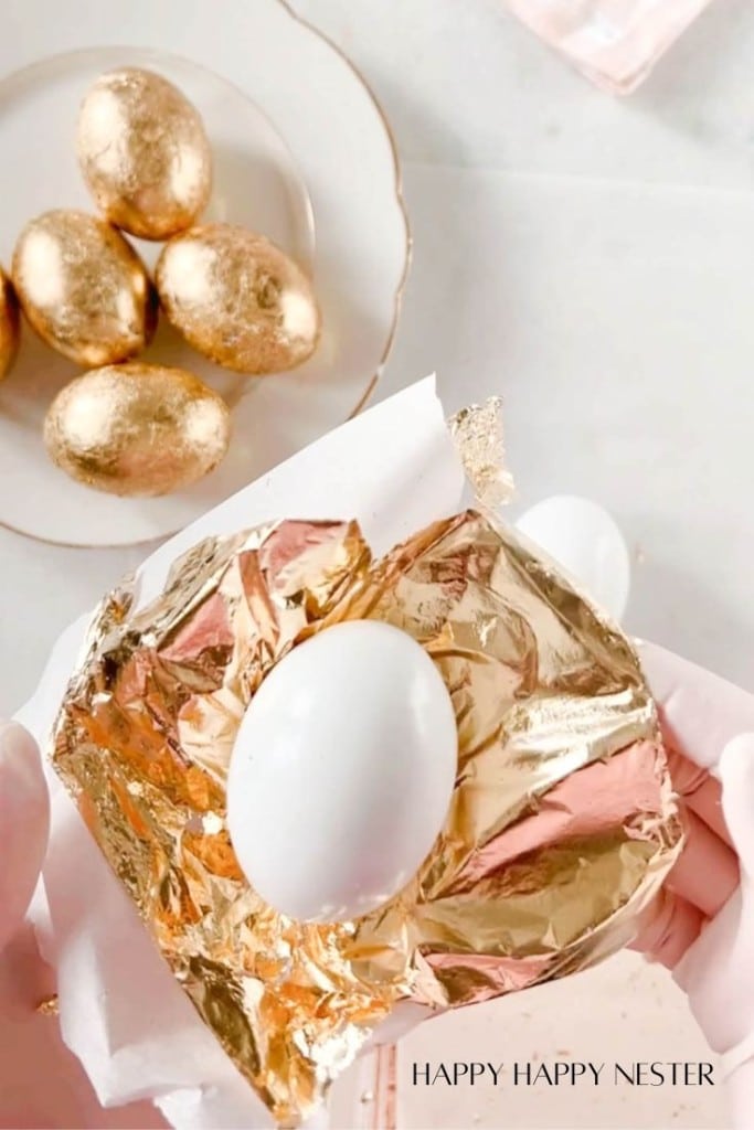 showing how to place the gold leaf sheet under the wooden faux egg