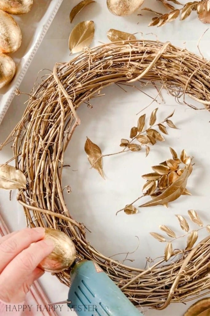 hot glueing a gold egg on a wreath