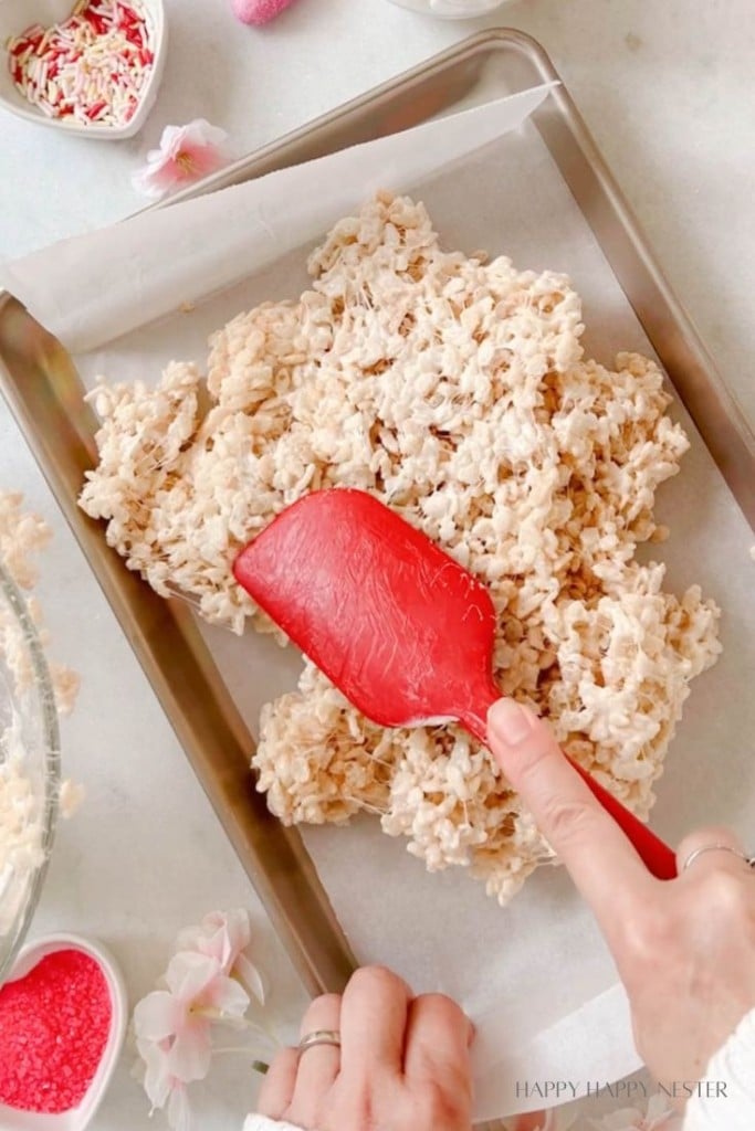 Patting down Valentine's Day rice krispie treats in a baking tray