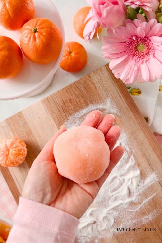 one orange mochi in the palm of a hand