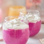 Pink Barbie drink recipe. A closeup of 2 glasses filled with the pink drink and whip cream on top.