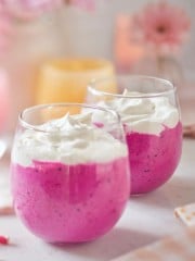 Pink Barbie drink recipe. A closeup of 2 glasses filled with the pink drink and whip cream on top.