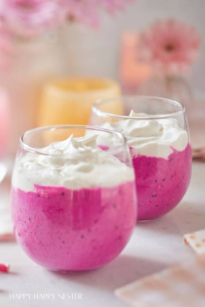 Pink Barbie drink recipe. A closeup of 2 glasses filled with the pink drink and whip cream on top.