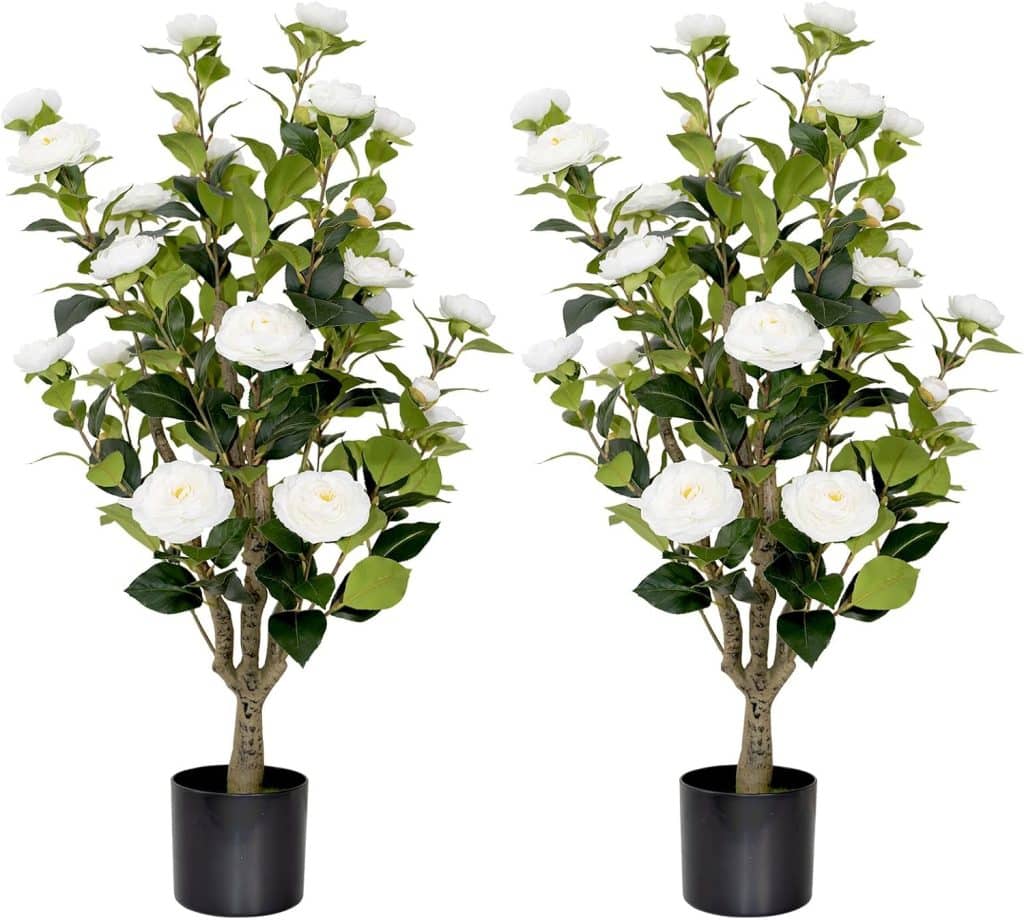 Two artificial potted plants with green leaves and white camellia flowers, each in a black pot, offer amazon style simple porch decor when placed side by side on a white background.
