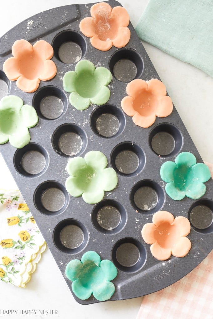 flower shaped cookie dough sitting in a mini muffin tin ready to be baked