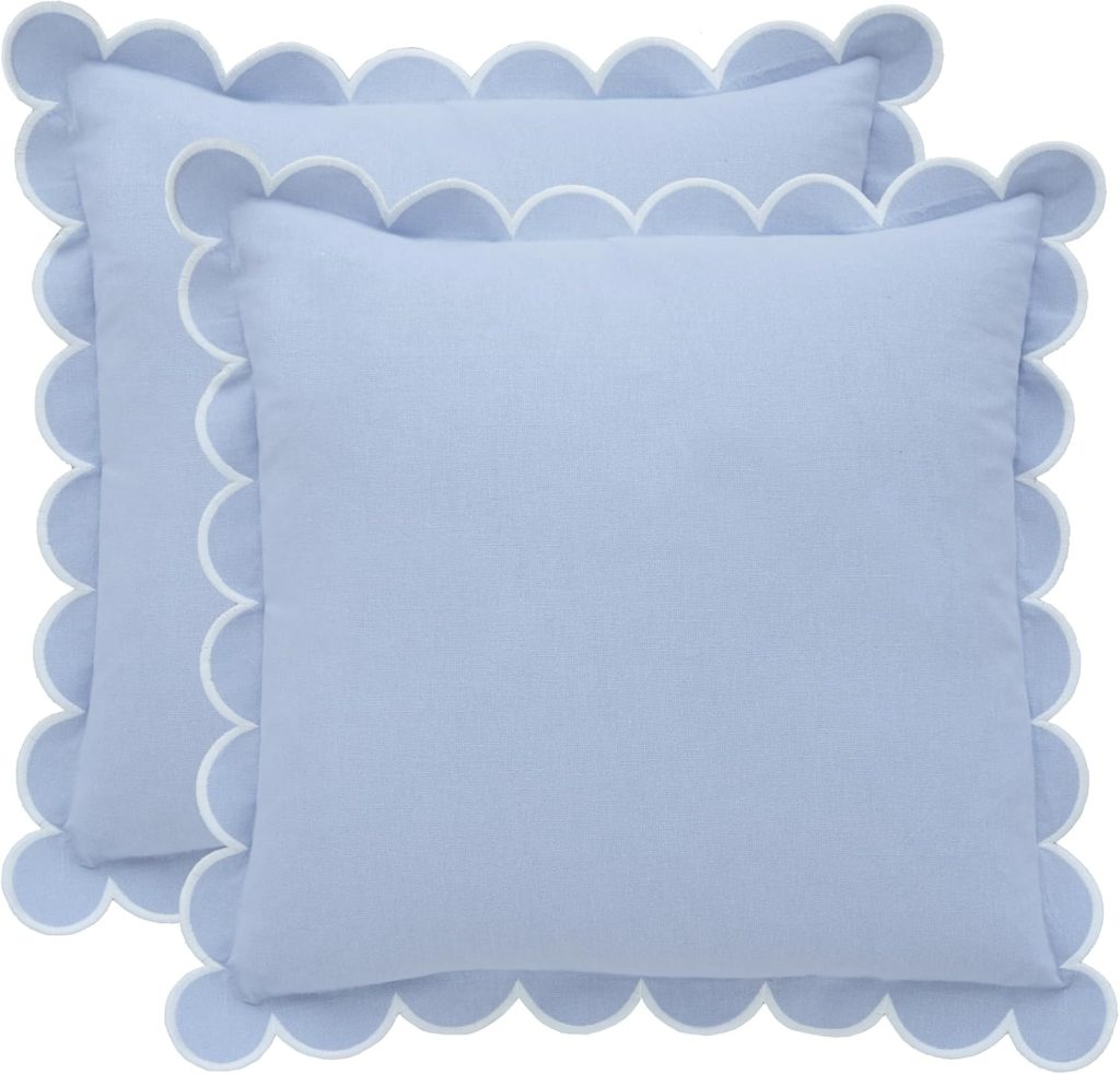 Two light blue springtime throw pillows with scalloped edges outlined in white, overlapping each other against a white background.