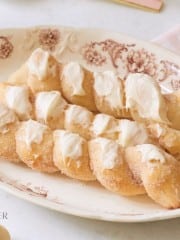 three breadsticks iced with cream cheese on a brown plate