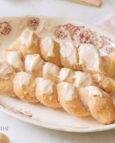 three breadsticks iced with cream cheese on a brown plate