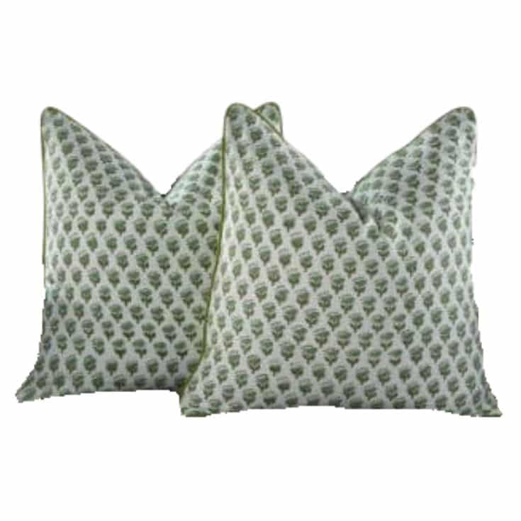 Two decorative springtime throw pillows with a white background and a repeating small green tree or leaf pattern, arranged overlapping each other.