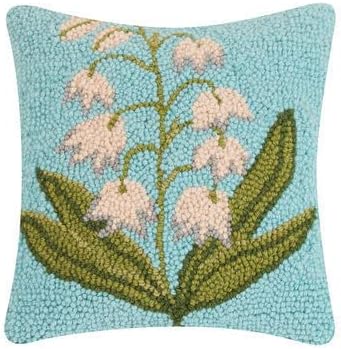 A decorative springtime throw pillow with a hooked texture, featuring white bell-shaped flowers and green leaves on a light blue background.