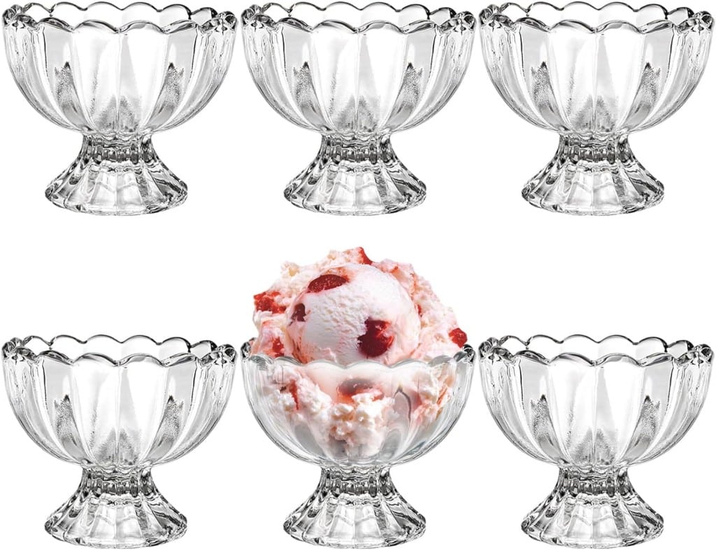 Five empty glass dessert bowls with a scalloped edge design are arranged around a sixth bowl in the center, which is filled with a scoop of strawberry ice cream. The central bowl, reminiscent of delicious lemon curd dessert recipes, is the focal point with the ice cream visible from a top angle.