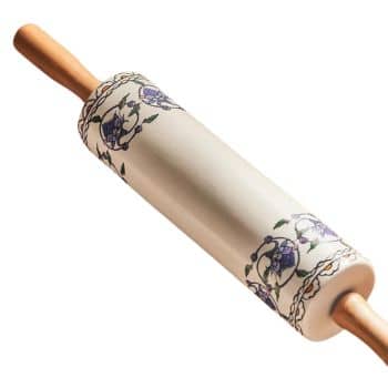 A ceramic rolling pin with wooden handles, decorated with a floral design featuring blue flowers and green leaves. The decorative pattern adds a touch of elegance to the otherwise functional kitchen tool.