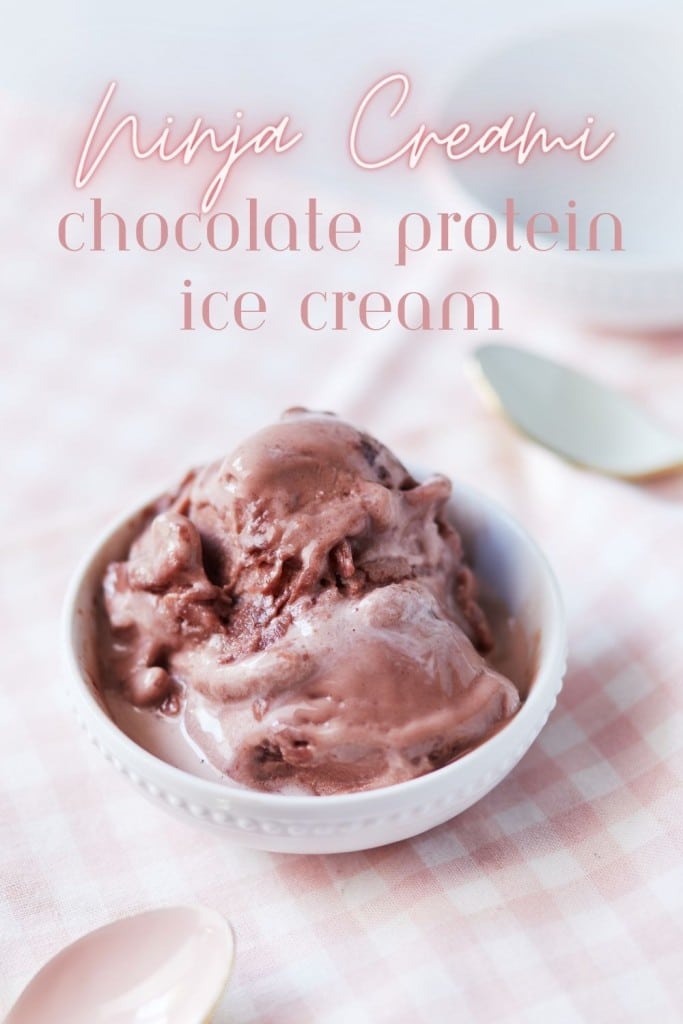A bowl of chocolate protein ice cream is placed on a pink and white checkered cloth. The text "Ninja Creami chocolate protein ice cream" is written in the top portion of the image. Next to the bowl are a white spoon and a partially visible background plate.