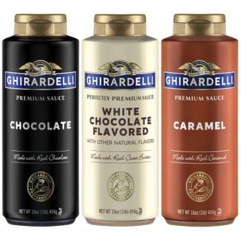 Three bottles of Ghirardelli Premium Sauce. From left to right: a black bottle labeled "Chocolate," a white bottle labeled "White Chocolate Flavored," and a brown bottle labeled "Caramel." Each bottle contains 16 oz (454 g) and features the Ghirardelli logo.