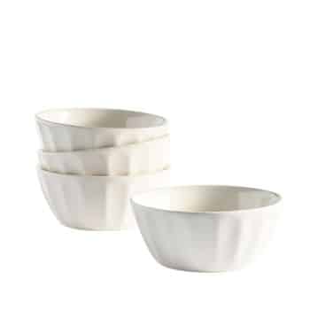 Four white ceramic bowls are stacked in pairs against a plain white background. The bowls are shallow with a scallop-like exterior design, creating a simple yet elegant appearance.