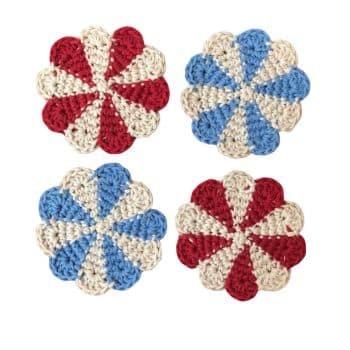 Four circular, hand-crocheted coasters are shown. Each coaster has a unique pinwheel design in red and white or blue and white colors. The alternating sections and scalloped edges give them a vibrant and textured appearance.