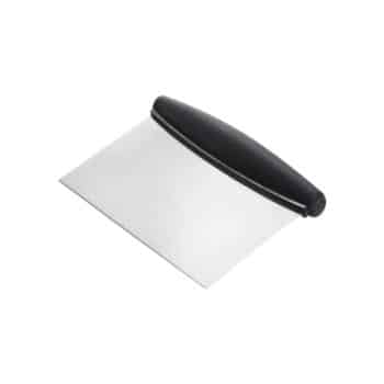 A metal bench scraper with a rectangular stainless steel blade and a black ergonomic handle, used for cutting and scraping dough or clearing surfaces in a kitchen.