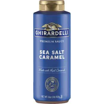 A blue bottle of Ghirardelli Premium Sauce, labeled "Sea Salt Caramel." The bottle indicates it is made with real caramel and contains 16 ounces (1 lb/454g) of sauce. The bottle has a gold cap and Ghirardelli's logo is displayed at the top.