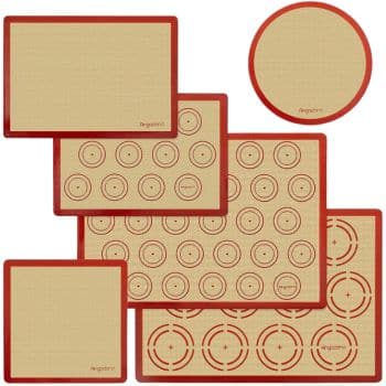 An assortment of six non-stick silicone baking mats in various shapes and sizes, all with red borders. The mats feature different patterns, including circles and target shapes, designed for precise baking and cooking.