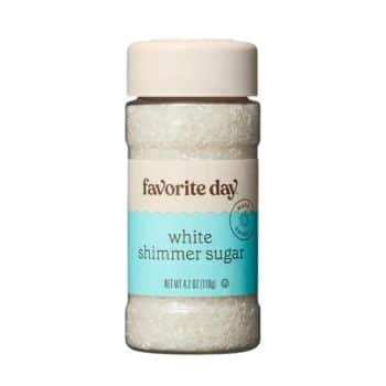 A bottle of "Favorite Day" white shimmer sugar. The bottle has a white and light turquoise label with the product name and net weight of 4.2 oz (119g). The bottle has a cream-colored cap and contains white, sparkling sugar crystals.