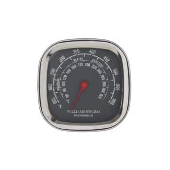 A square oven thermometer with a black face and a stainless steel frame. The dial ranges from 100°F to 600°F, with temperature markings in both Fahrenheit and Celsius. The red needle is pointing to approximately 100°F. The brand "Williams Sonoma" is printed on the face.