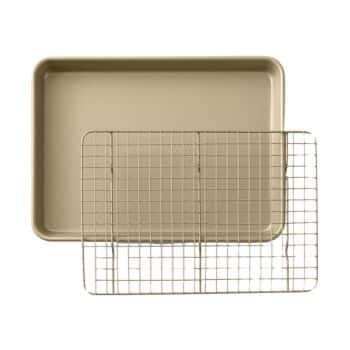 A beige rectangular baking sheet is placed with a metal cooling rack. The cooling rack is slightly angled and rests on top of the baking sheet, with its wire grid pattern visible. The background is white, making the items clearly stand out.