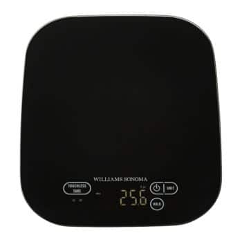 A black digital kitchen scale with a white LED display showing a weight of 25.6 grams. The scale features touch buttons for tare and unit conversion, and the brand "Williams Sonoma" is visible above the display.