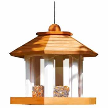 A wooden bird feeder with a hexagonal roof and multiple seed compartments hangs from a thin wire. The feeder, in a natural wood color, features a slightly conical roof and transparent panels, making it an excellent addition to your flower garden decor ideas while allowing birds easy access to the seeds inside.