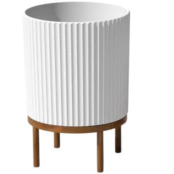 A modern, cylindrical white planter with vertical ribbing sits on a simple, four-legged wooden stand. The planter has a sleek and minimalist design, ideal for contemporary interior decor and perfect for inspiring flower garden decor ideas.